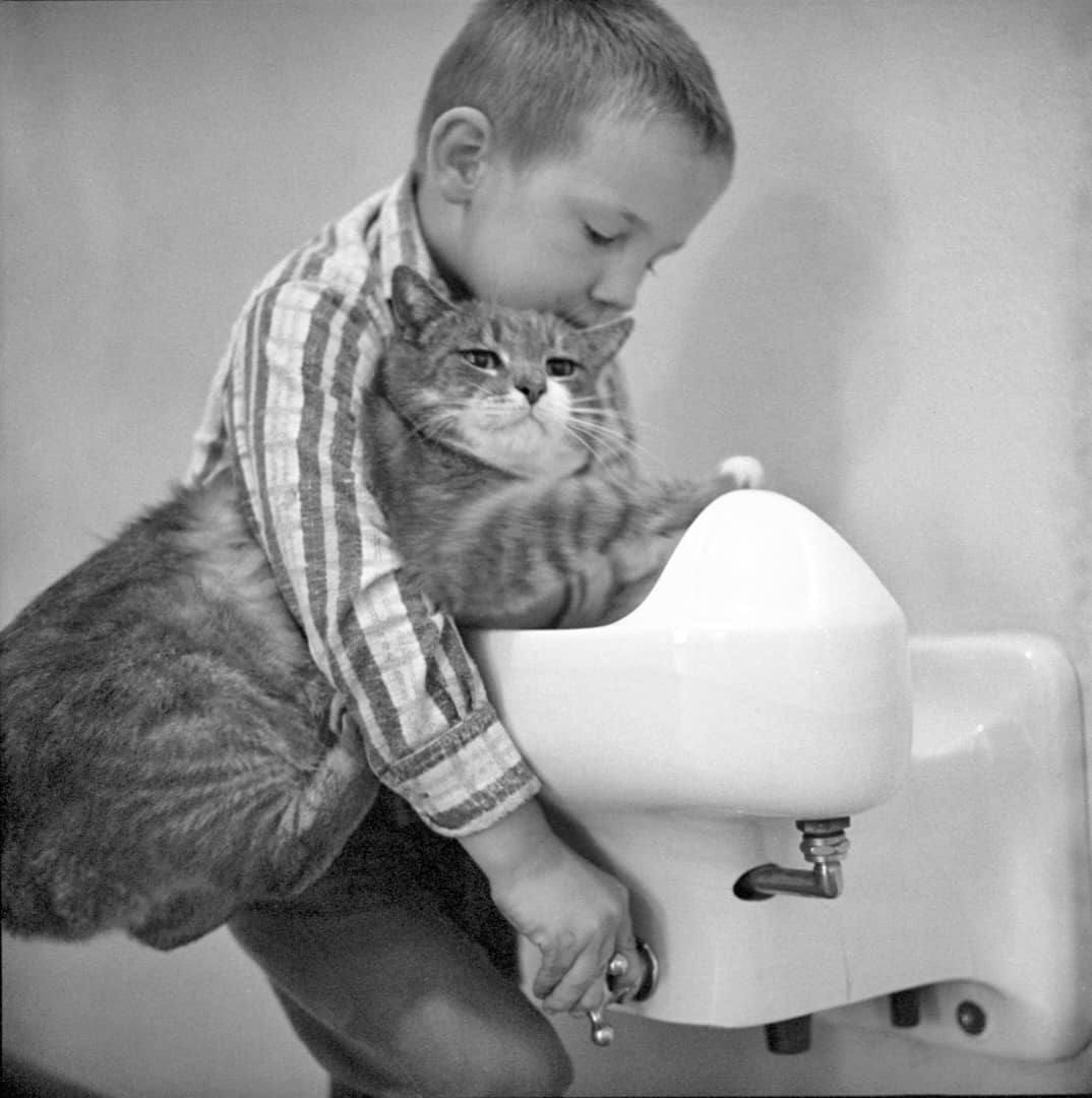 Young boy hugging Room 8 while getting a drink from water fountain